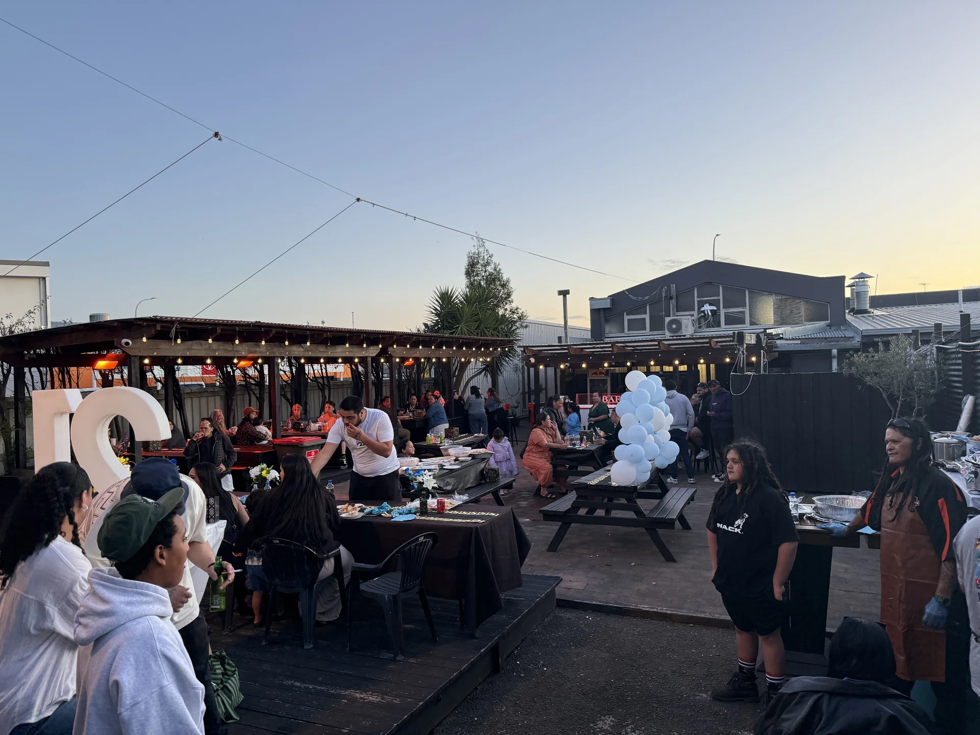A twenty-first party in the garden bar at dusk, with guests at long tables and white balloons